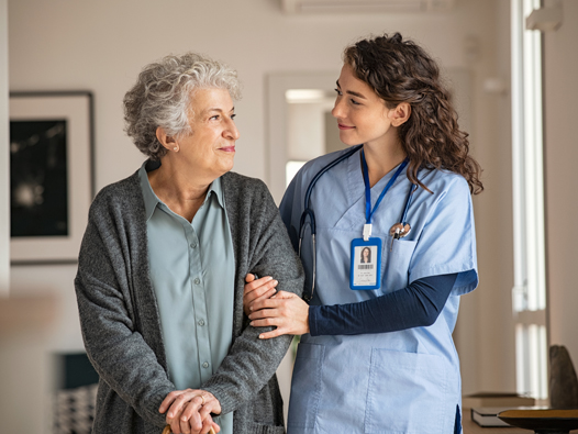 A caregiver helping a senior client walk through a sunlit living room