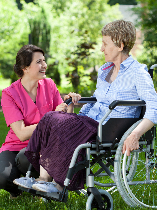 A caregiver sitting with an older adult client at their kitchen table, sharing a warm conversation at home